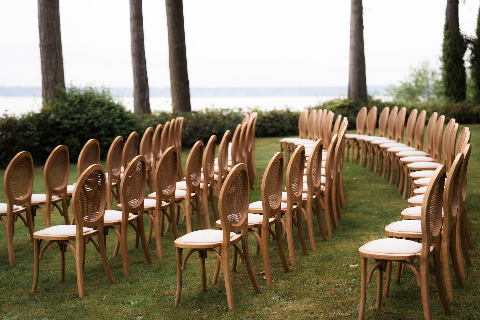 Waterfront wedding ceremony seating framed by trees