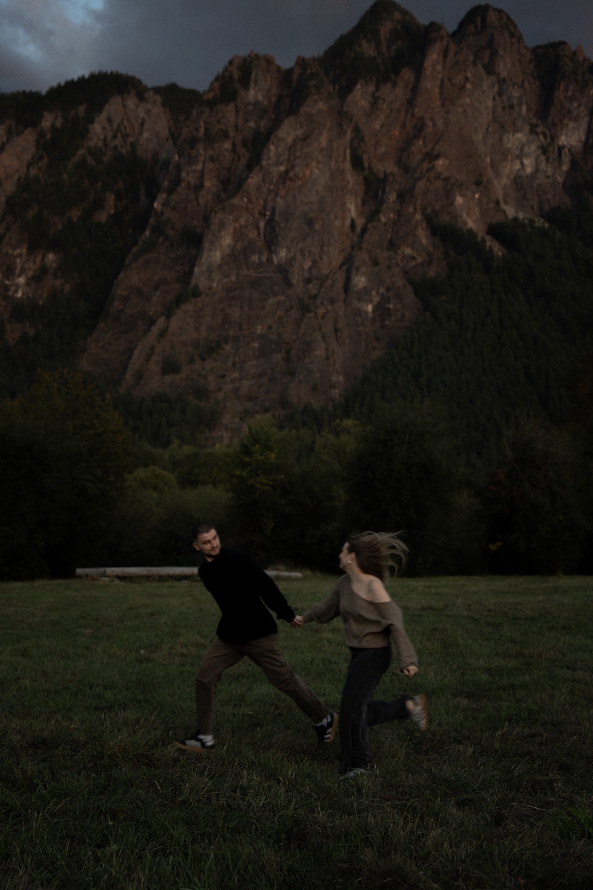 Engaged couple running together through a mountain meadow in Washington