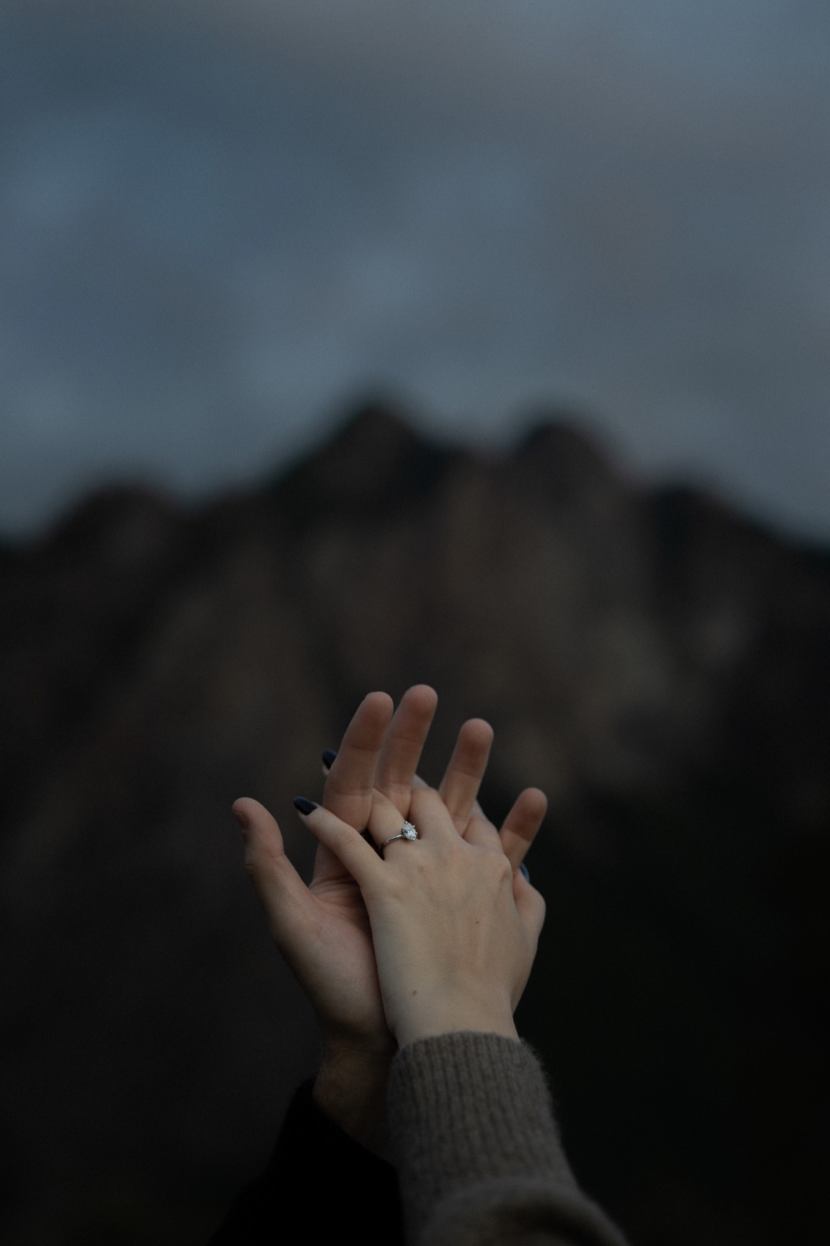Close detail of an engagement ring and the couple holding hands